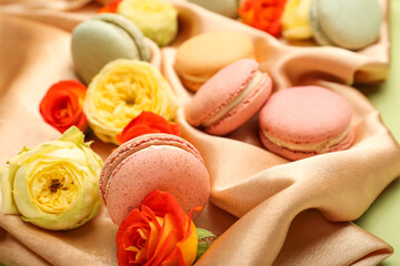 Sweet macaroons and rose flowers on fabric background, closeup. International Women's Day celebration