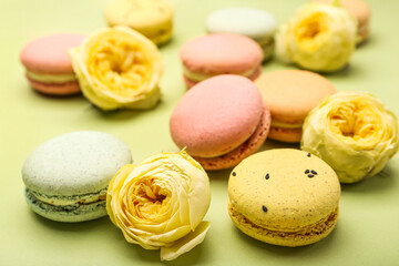 Sweet macaroons and rose flowers on green background, closeup. International Women's Day celebration