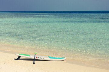 Sup Board on sandy beach in Maldives with writing 