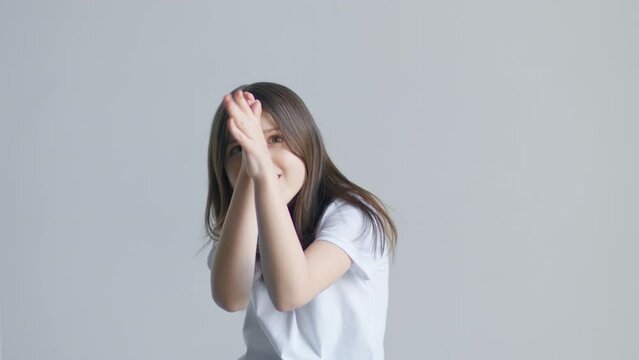 A teen girl mocking, makes faces and apes in front of a white background