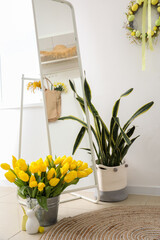 Bucket with tulips and Easter bunnies on floor in room