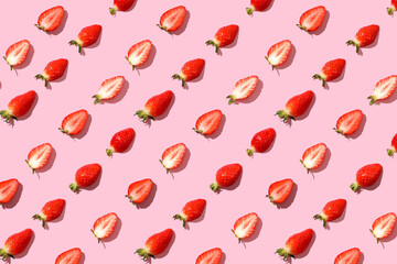 Strawberries laid out horizontally side by side on pink paper in a row