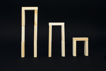 Wooden boards in the form of vertical frames on a black background. Three wooden frames from highest to lowest. Wooden constructor for the development of dexterity and concentration