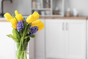 Vase with bouquet of tulips and hyacinth flowers in kitchen