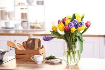 Delicious breakfast and vase with flowers on kitchen counter