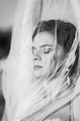 Black and white portrait of a beautiful girl in a dress with a veil close-up. The wind develops hair and fabric. Concept - fashion photography