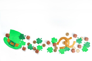 St Patrick flatlay background with shamrock clover leaves, leprechaun hat decor, golden coins and...