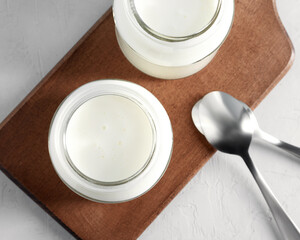 Yogurt, kefir or fermented milk product in glass jars on a wooden board. Healthy food concept. Flat lay