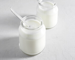 Yogurt, kefir or fermented milk product in glass jars on a white table. Healthy food concept
