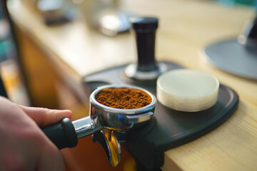 barista tempering ground coffee into espresso pitcher