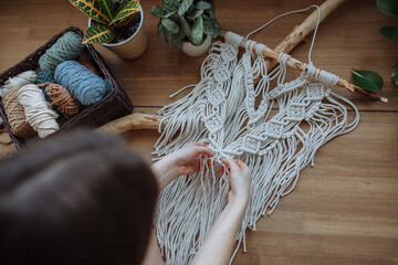 A girl weaves a panel using macrame technique