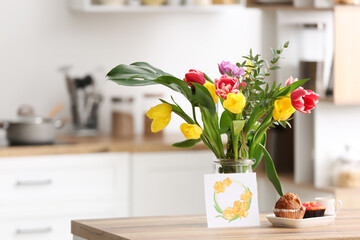 Vase with flowers, breakfast and greeting card on dining table