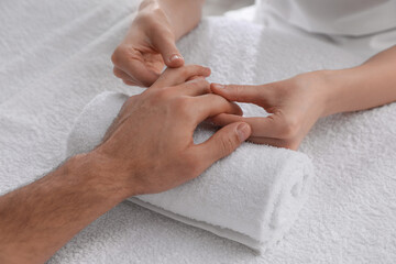 Obraz na płótnie Canvas Man receiving hand massage on soft towel, closeup