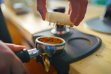 barista tempering ground coffee into espresso pitcher