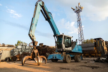 Large tracked excavator working a steel pile at a metal recycle yard. Industrial scrap metal recycling - selective focus, copy space