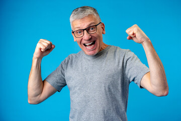 Middle aged man happy and excited celebrating success over blue background