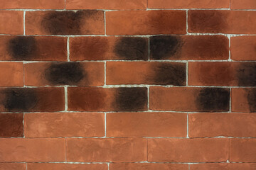 Part of the wall of the building is made of red-brown brick with black spots for use as an abstract...