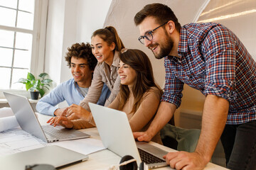 Group of casually dressed young students discussing ideas at the office about new startup project.	
