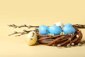 Willow branches and nest with painted Easter eggs on yellow background