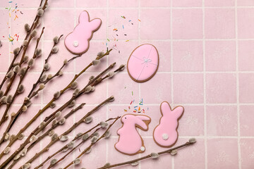 Willow branches and Easter cookies on pink tile background