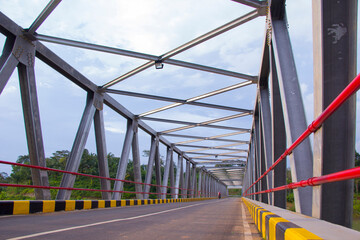 Fototapeta na wymiar Perspective view of a metal highway bridge over a river in Pringsewu, Lampung.