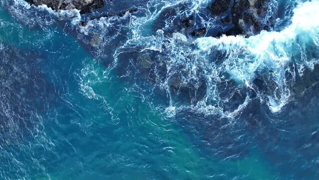 Colorful waters of the ocean, swirl around the rocky and scenic coastline. Sea waves breaking over rocks.