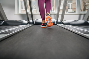 Woman feet run at gym treadmill indoors