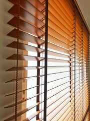Brown wooden blinds on windows of rooms inside house.