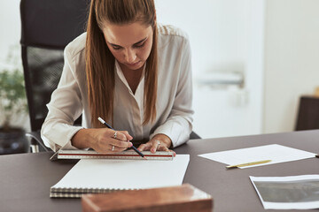 Young female architect working on designs at her office desk