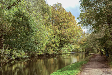 Fototapeta na wymiar A peaceful scene along the tow path of the Leeds and Liverpool Canal between Bingley and Shipley is an ideal spot to take a relaxing stroll and enjoy the reflections in the gently moving water