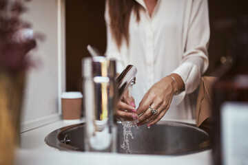 Young woman washing her hands in her sink at home