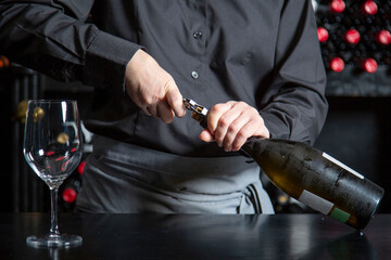 Faceless bartender opening wine bottle