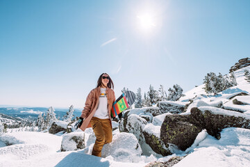 Russia. Sheregesh. Girl snowboarder in black sun goggles in winter in sunny weather outdoors among...