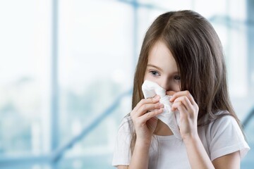 Young kid feels unwell, blows nose in tissue, suffers from running nose, cold symptoms or allergy