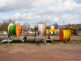 Wooden rollers with multi-colored fiber optic cables for laying data cables on a construction site.