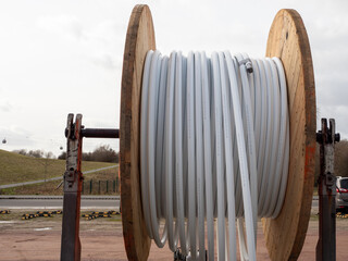 Wooden roller with white fiber optic cables for laying data cables at the construction site.