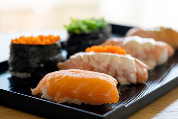 seawed maki and salmon nigiri sushi close up on black traditional tray over white background