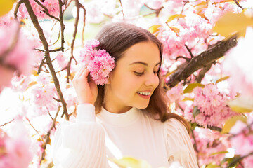 Fototapeta premium smiling teen girl at sakura flower bloom in spring