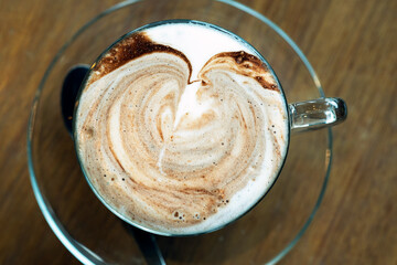 Close up White Latte Coffee Cup, Decorated with abtract pattern milk foam on top in cleared glass