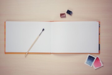 The artist's desktop, the spread of a rectangular sketchbook with paints, brushes, a mockup for the image