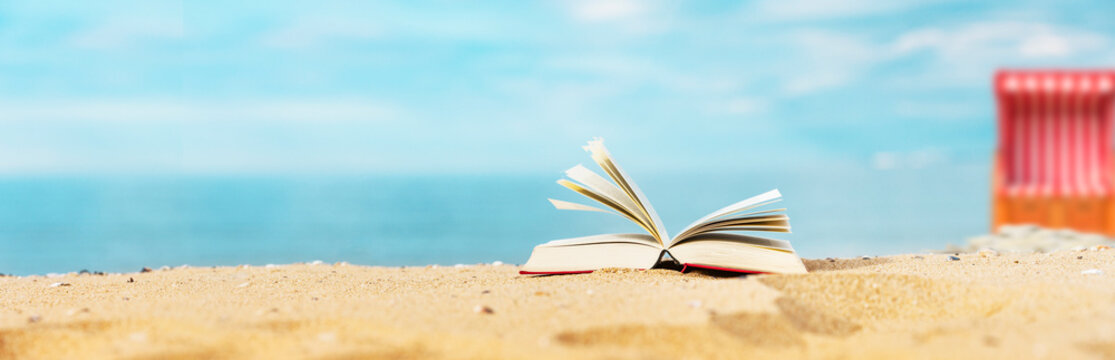 Buch am Strand mit Meer im Hintergrund