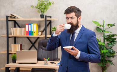 brutal ceo in businesslike suit has lunch break with coffee cup at office, morning
