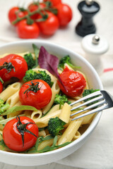 Bowl of delicious pasta with tomatoes, arugula and broccoli on white table, closeup