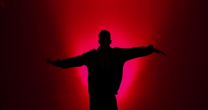 Silhouette of young man breakdancing in red light background