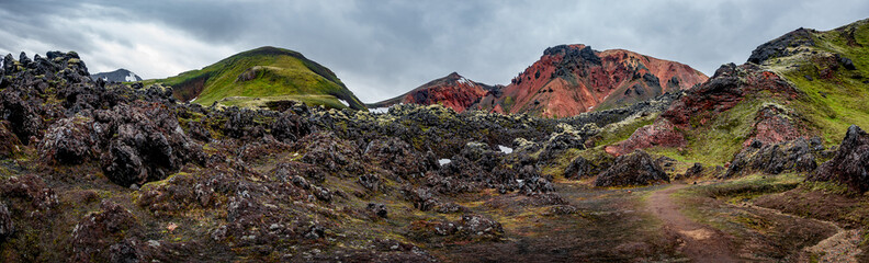 Beautiful panoramic Icelandic landscape of colorful rainbow volcanic Landmannalaugar mountains, at famous Laugavegur hiking trail with dramatic snowy sky, and red volcano soil in Iceland.