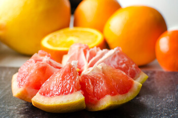 Different citrus fruits lie on the windowsill. Close-up, selective focus. Oranges, tangerines and peeled grapefruit. The concept of healthy natural food containing vitamins.