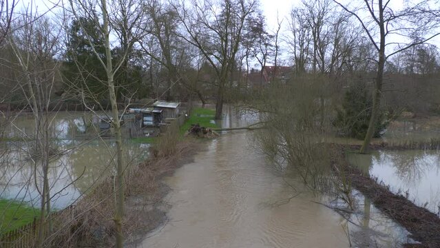 due to heavy rainfall and storm a river overflowed its banks and flooded the gardens and meadows