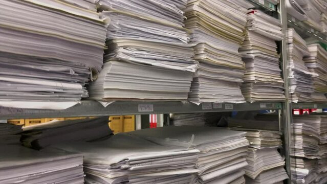 in a file archive there are shelves filled with stacks of paper