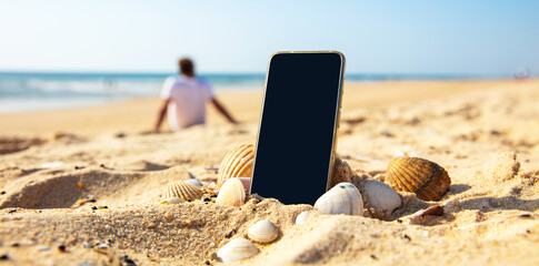 mobile phone on the beach and people silhouette relaxing