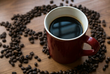Selective focus of a cup of coffee with a roasted coffee beans at the background.
